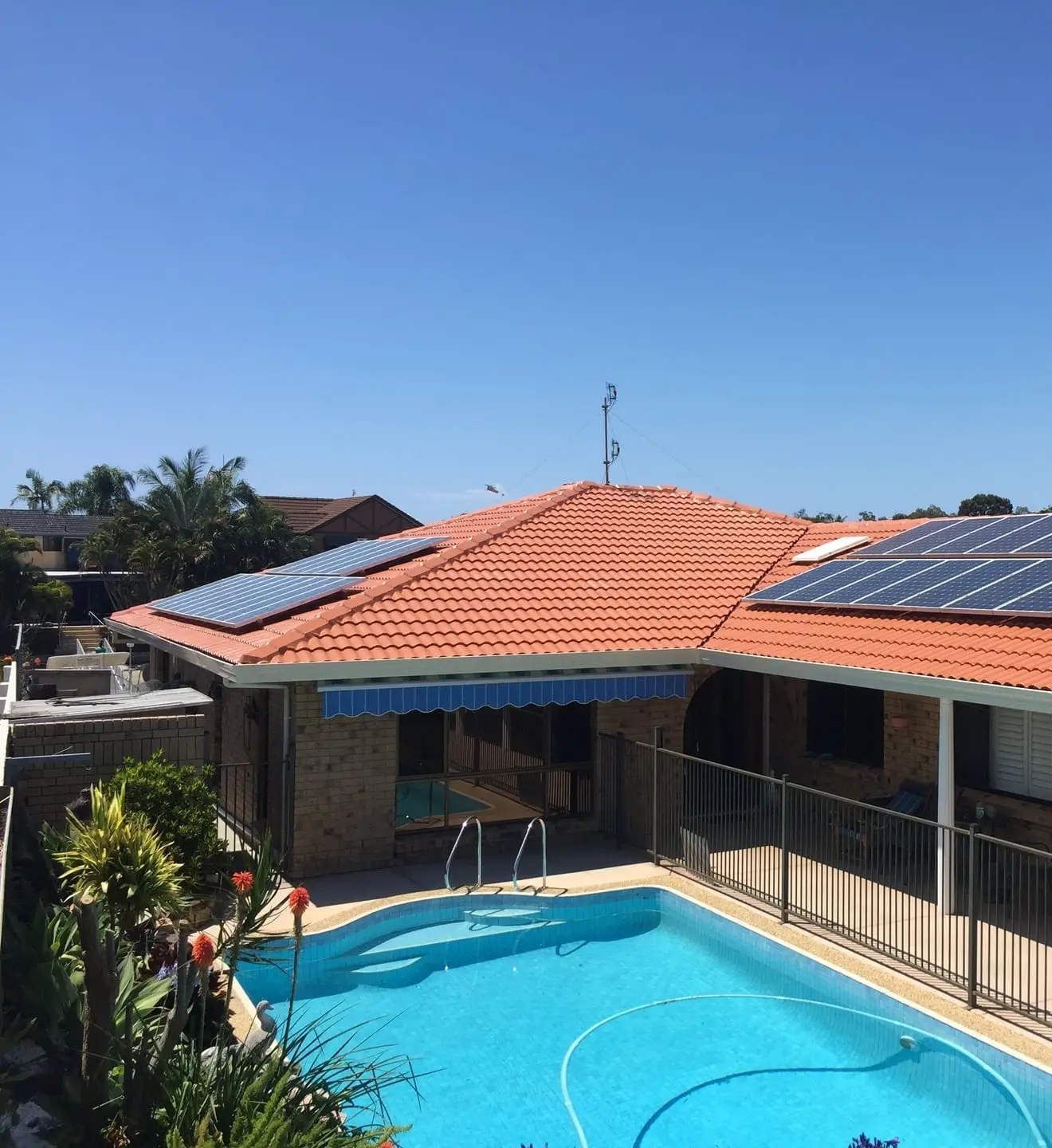 Restored terracotta tile roof with solar panels above a backyard pool