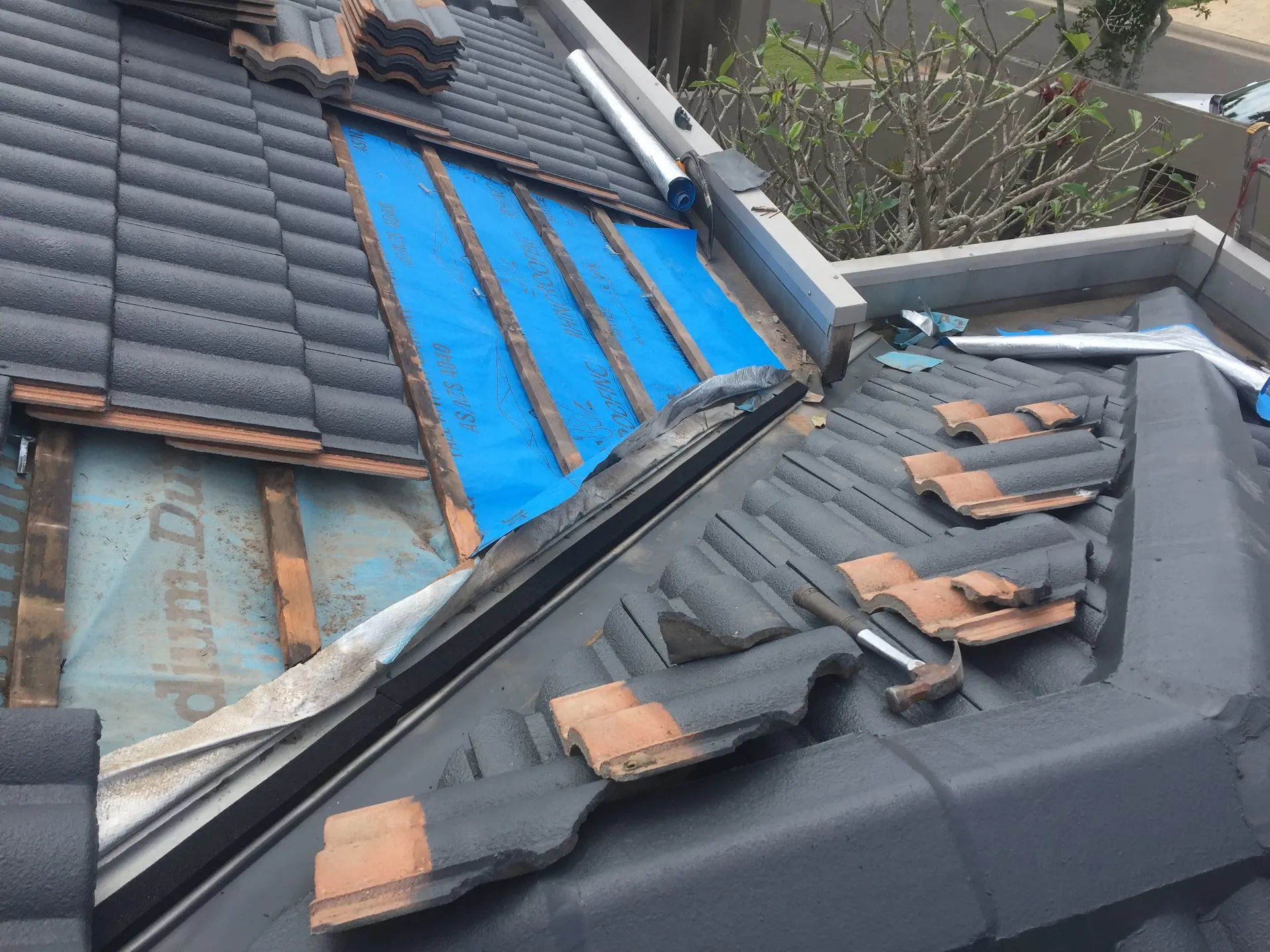 Tile roof valley opened during repairs, showing sarking beneath the tiles